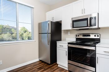 a kitchen with white cabinets and stainless steel appliances at Missions at Chino Hills, Chino Hills, CA
